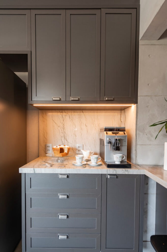 Perfil de led instalado abaixo dos armários e, logo acima da área onde fica a cafeteira. / Projeto de apartamentoda arquiteta Luana Ogata e foto de Emerson Rodrigues