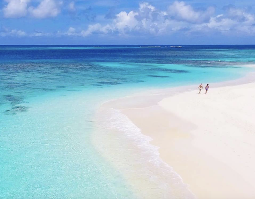 Praia de Anguilla, ilha caribenha com mar azul e areia branca. Casal caminhando ao fundo.