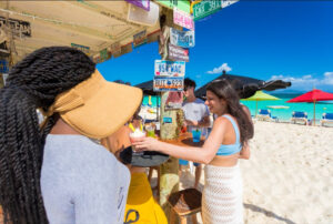 Pessoas em um bar em uma praia de areia brancas e mar azul turquesa.